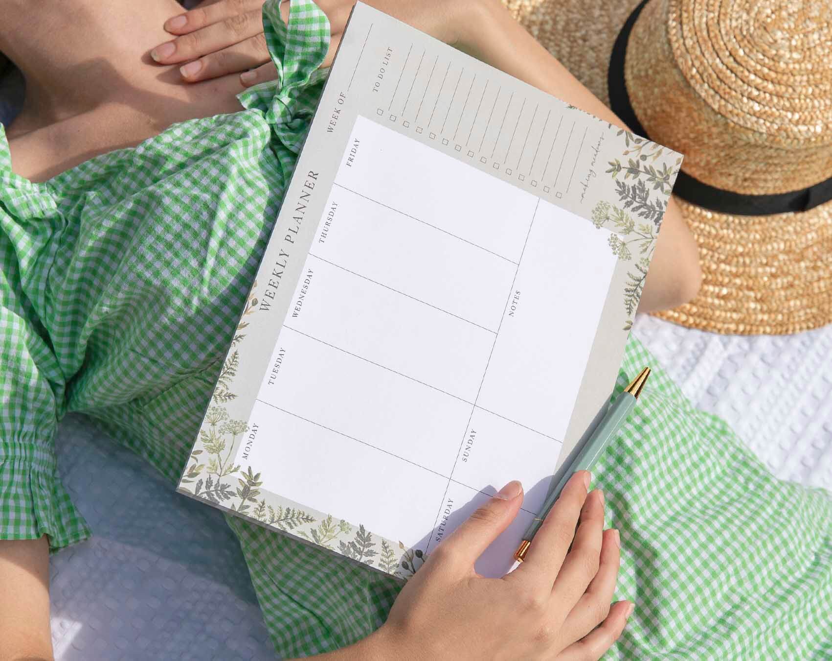 A woman holding a wedding planning stationery weekly planner for effective event organization.