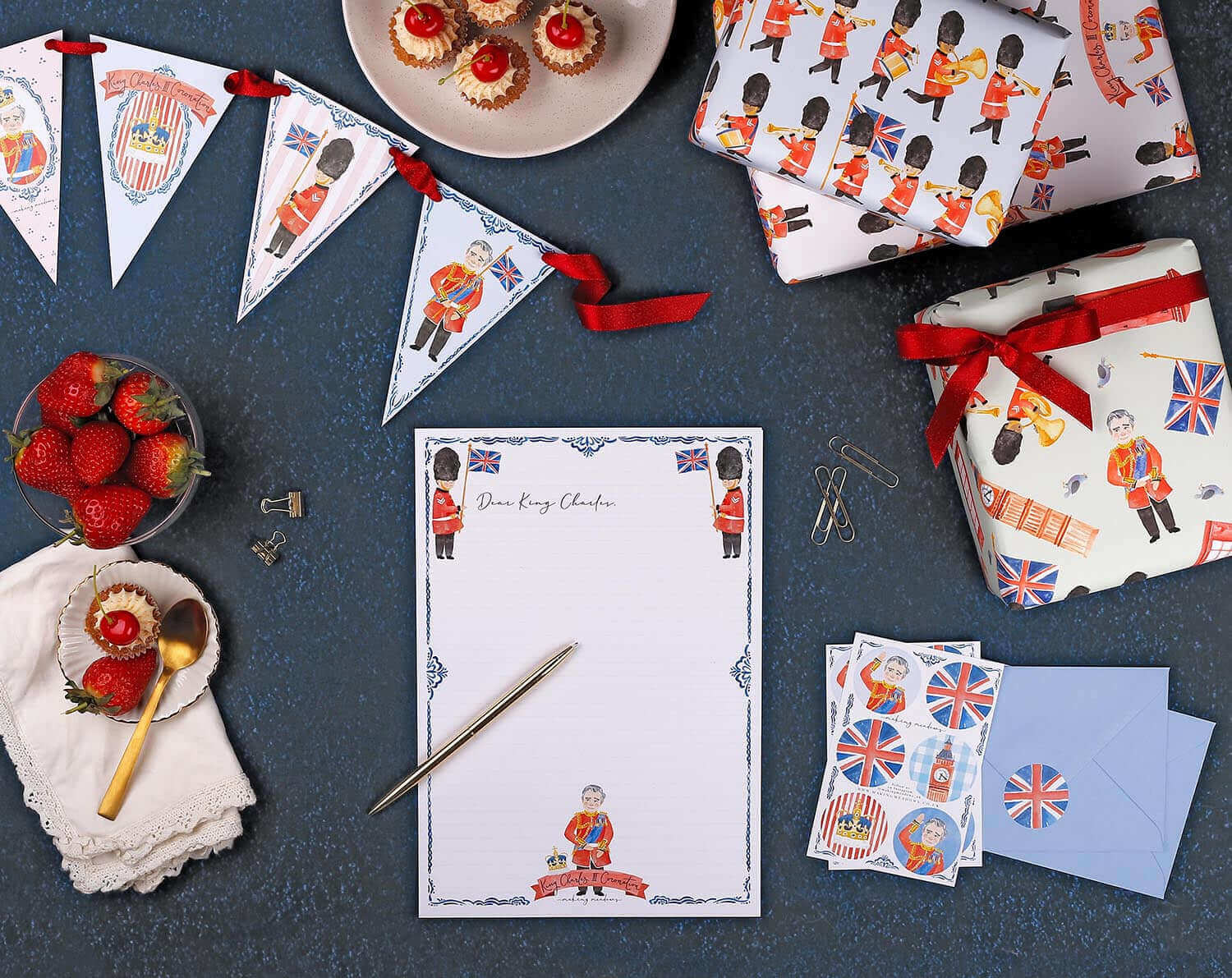 What You Need To Know About King Charles Coronation themed stationery, banners, and treats on a blue background.