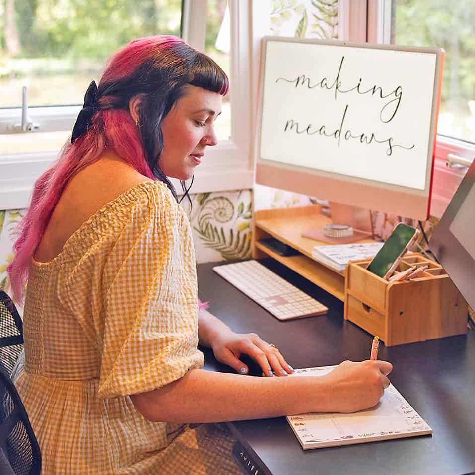 A woman in a home office writing notes, promoting ideas for an Eco-Friendly Home Office.