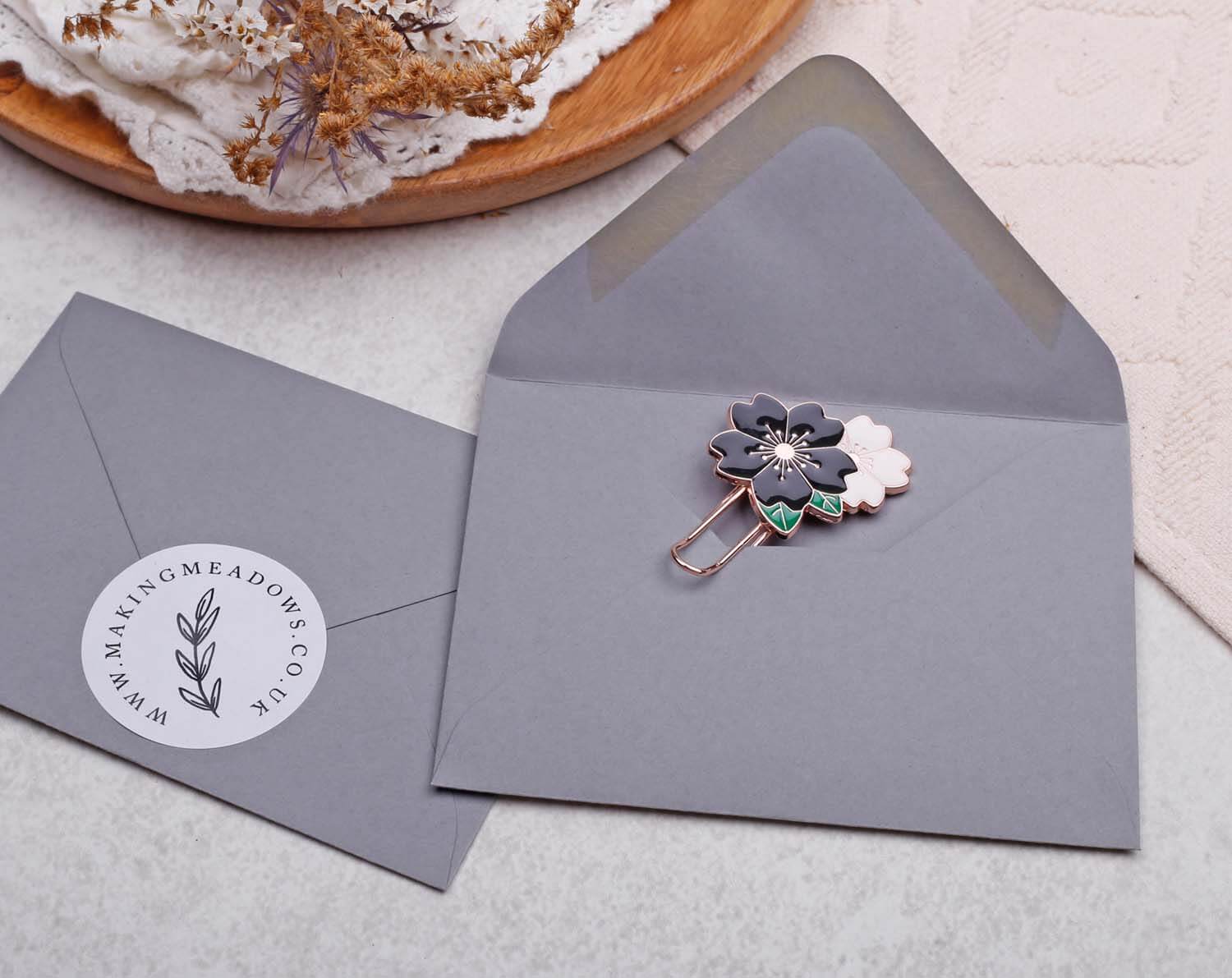 Black Flower Paper Clips elegantly displayed on a grey envelope, showcasing floral design details.