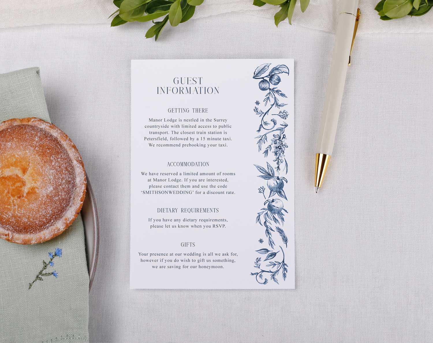 Blue Garden Wedding Information Cards displaying guest details on a decorative floral background with a pen and pastry.