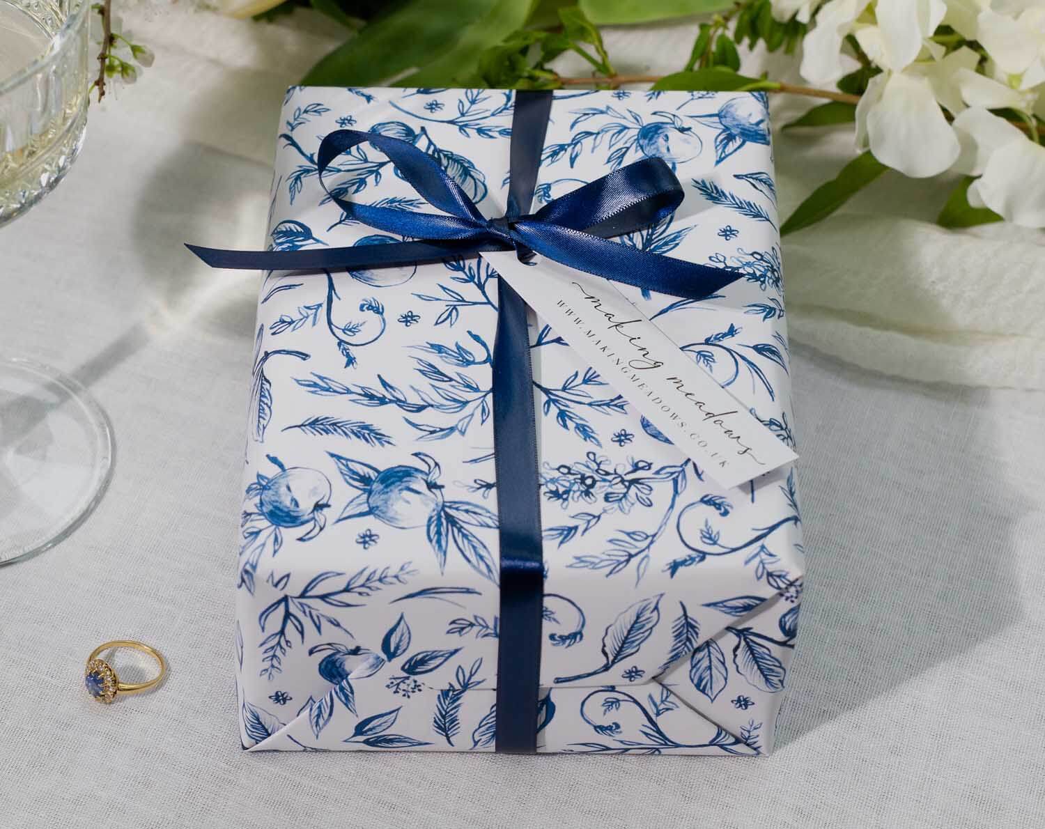 Blue Garden Wedding Wrapping Paper on a beautifully wrapped gift with a navy ribbon and floral design.