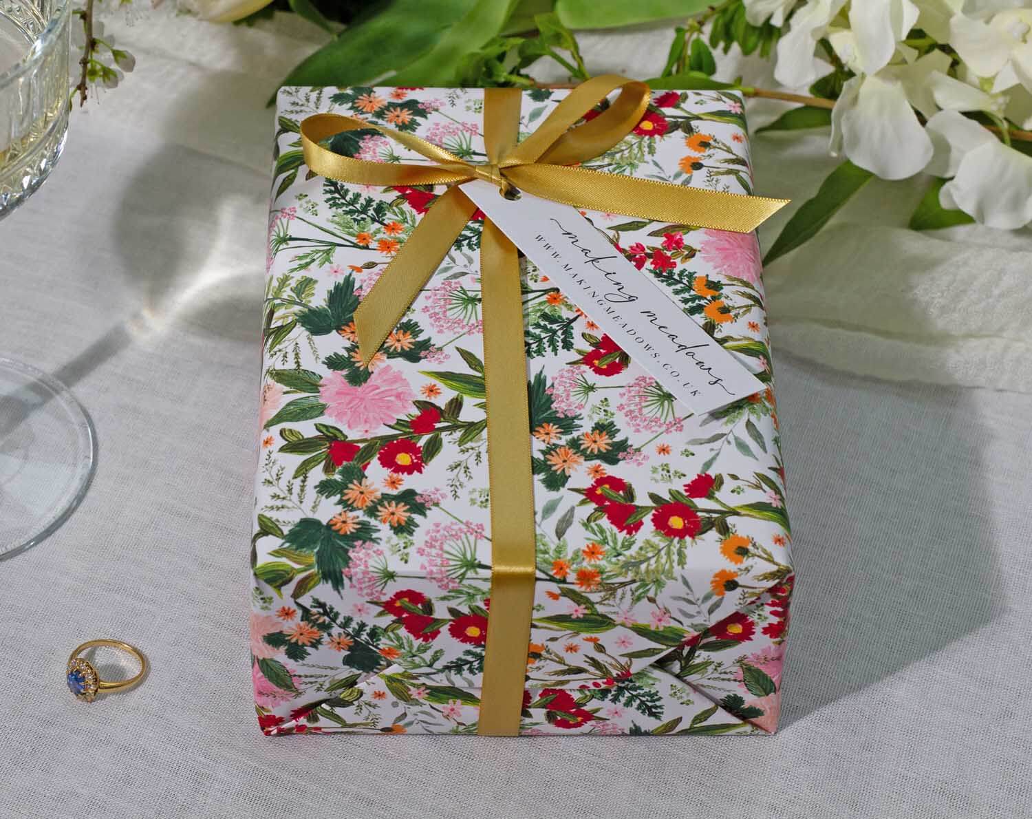Boho Wedding Wrapping Paper beautifully wraps a gift with floral design and golden ribbon, perfect for celebrations.
