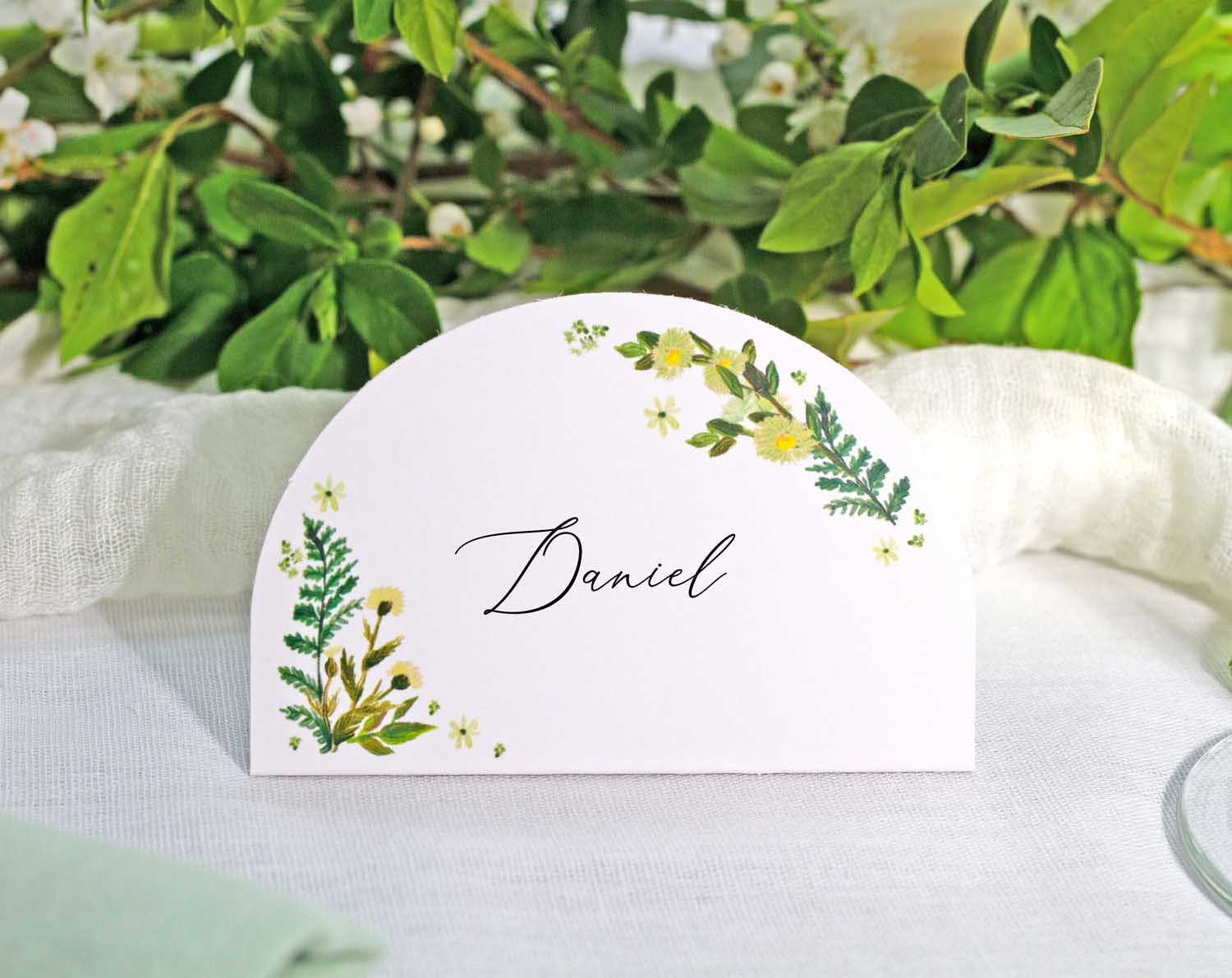 Botanical Wedding Place Cards featuring greenery and a handwritten name for elegant table settings.