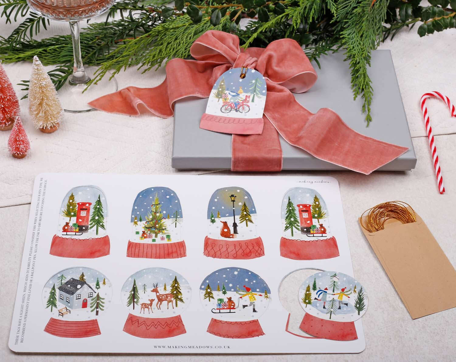 Snow Globe Christmas Gift Tags - 16 Pack displayed on a gift with a bow and seasonal decorations.
