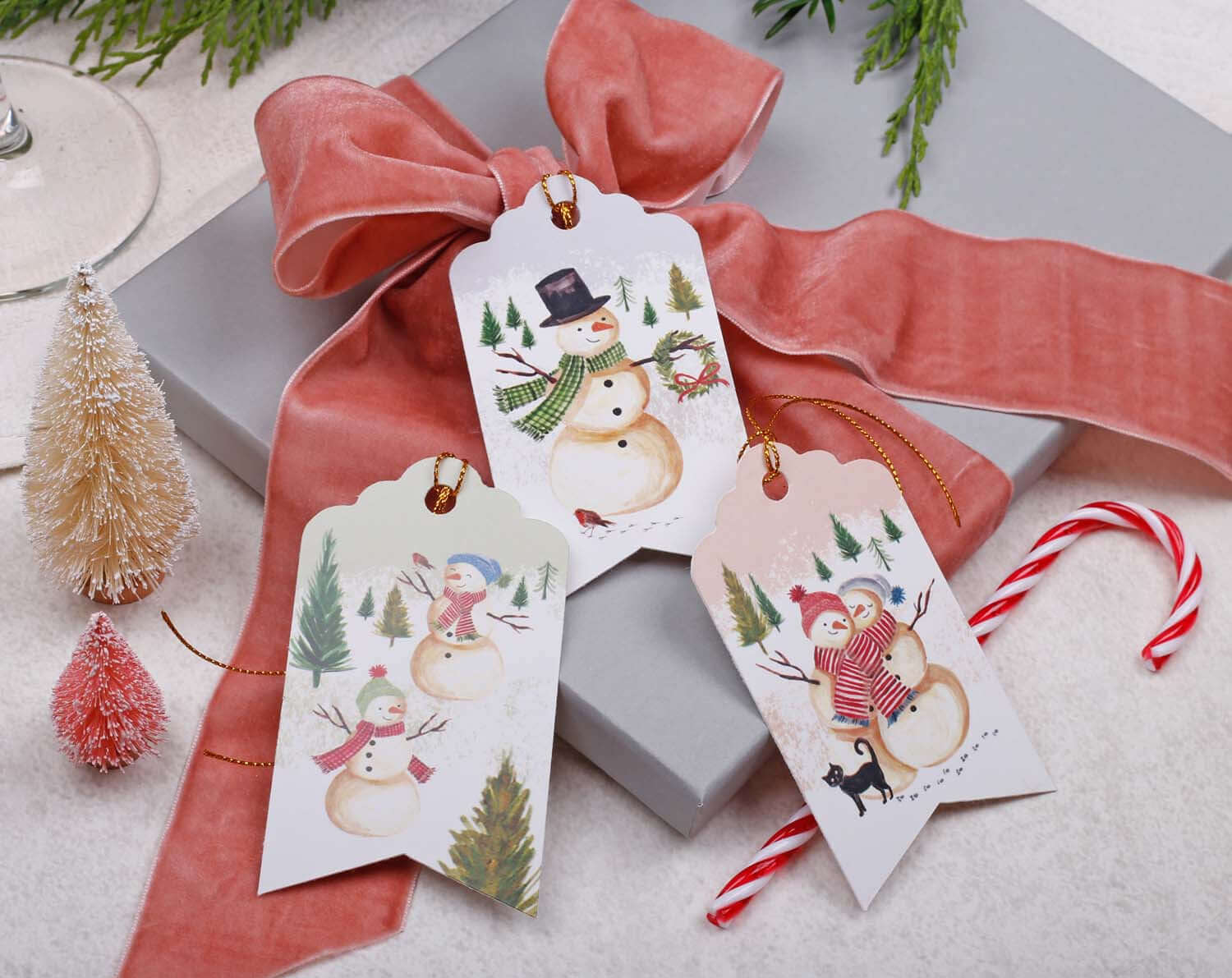 Snowman Christmas Gift Tags featuring cheerful illustrations, perfect for festive wrapping, set on a gift with ribbon.