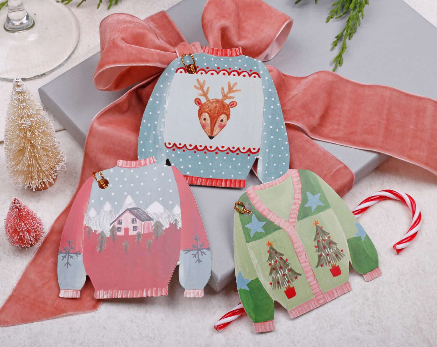 Colorful Christmas Jumper Gift Tags displayed on a festive package with ribbon and decorations.