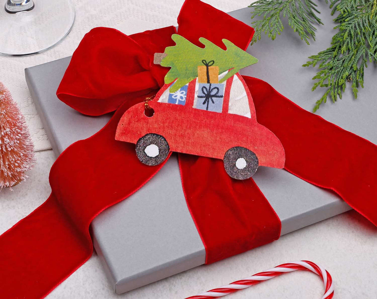 Car Christmas Gift Tags on a Christmas gift wrapped in red ribbon with a festive decoration.