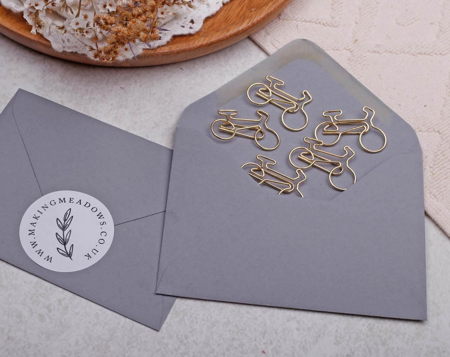 Gold Bicycle Paper Clips in an envelope, showcasing quirky gold stationery for crafts and organization.