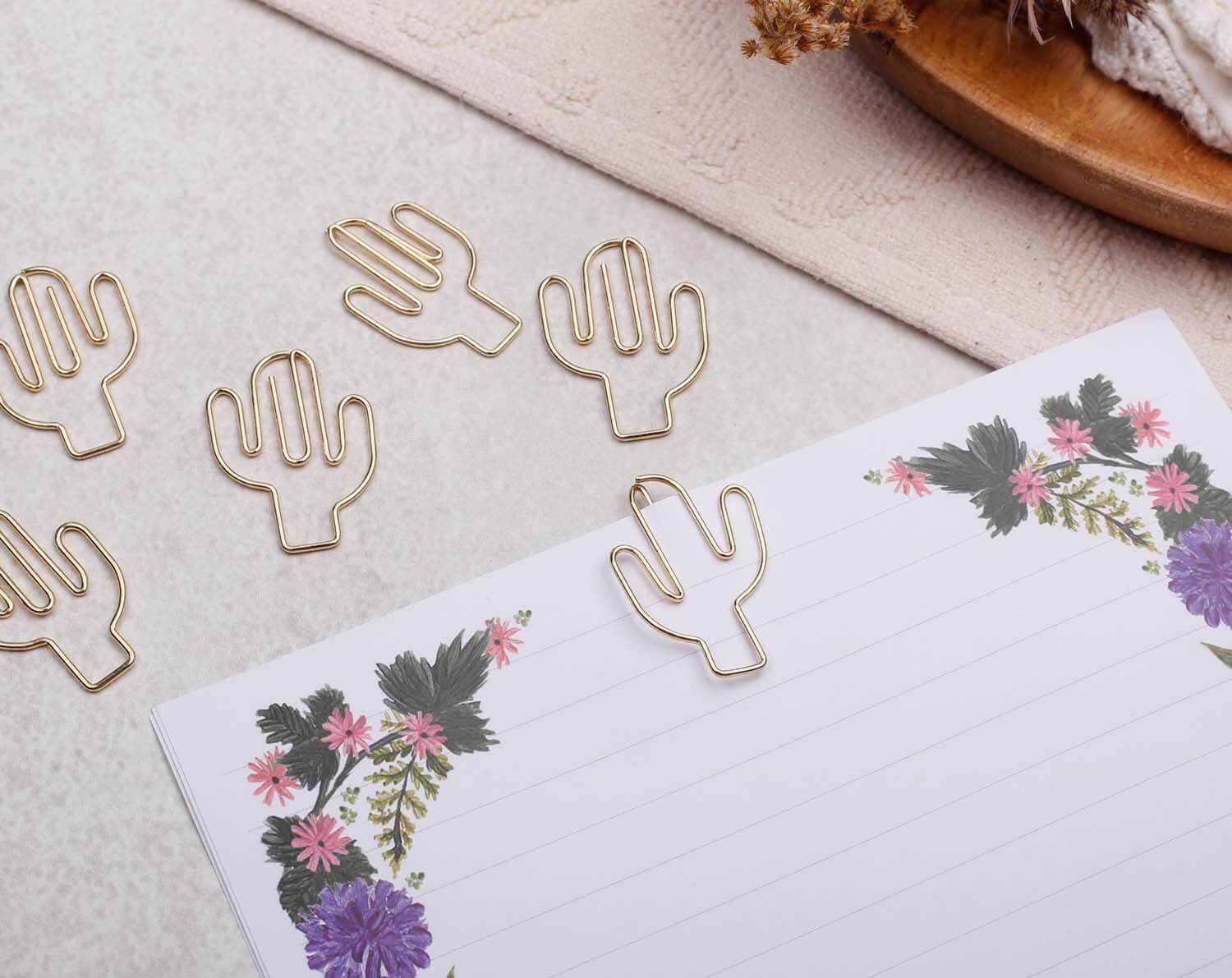 Gold Cactus Paper Clips in playful cactus shapes on a floral notepad, perfect for cheerful stationery.