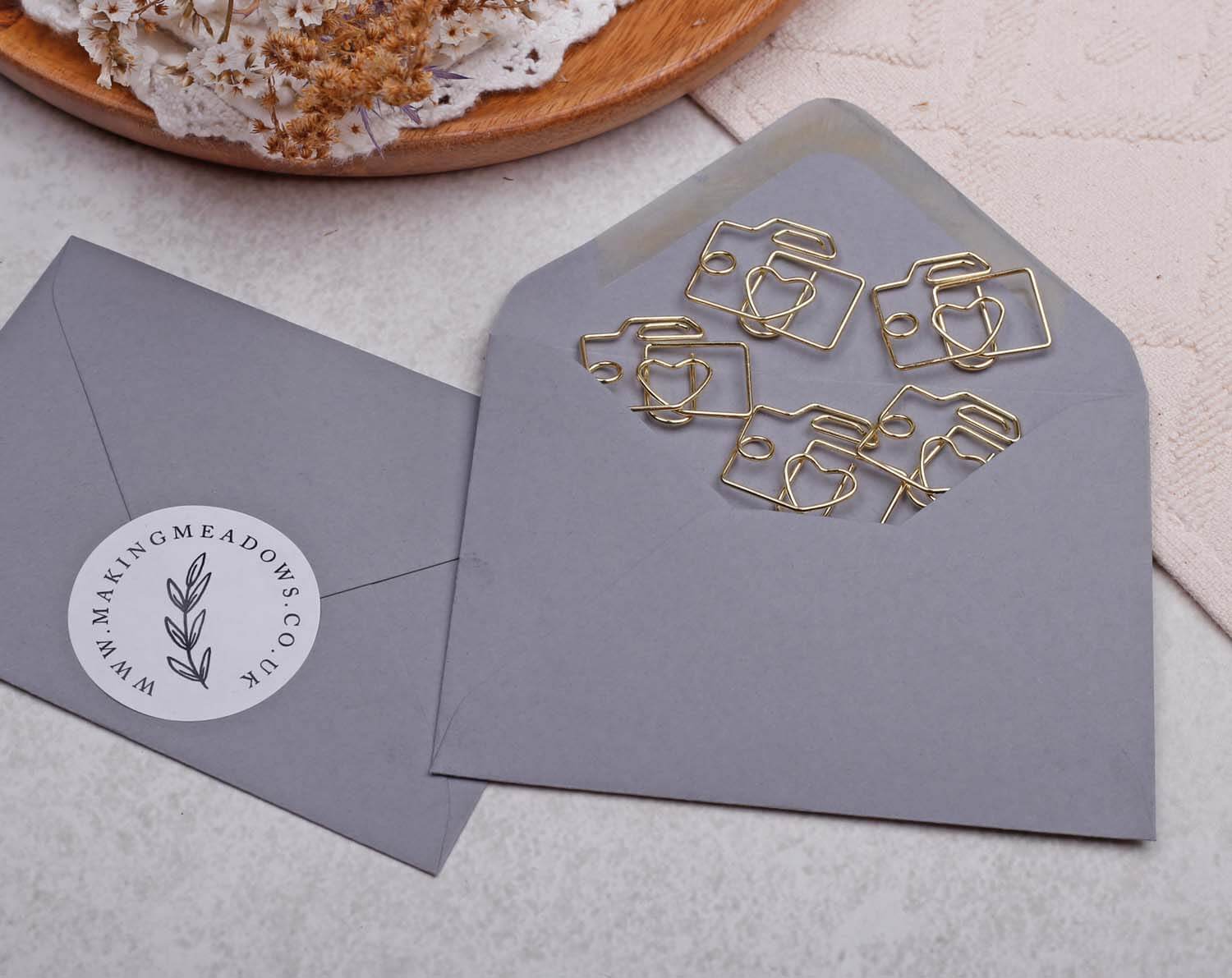 Gold Camera Paper Clips arranged in a gray envelope, showcasing a unique stationery design for photography lovers.