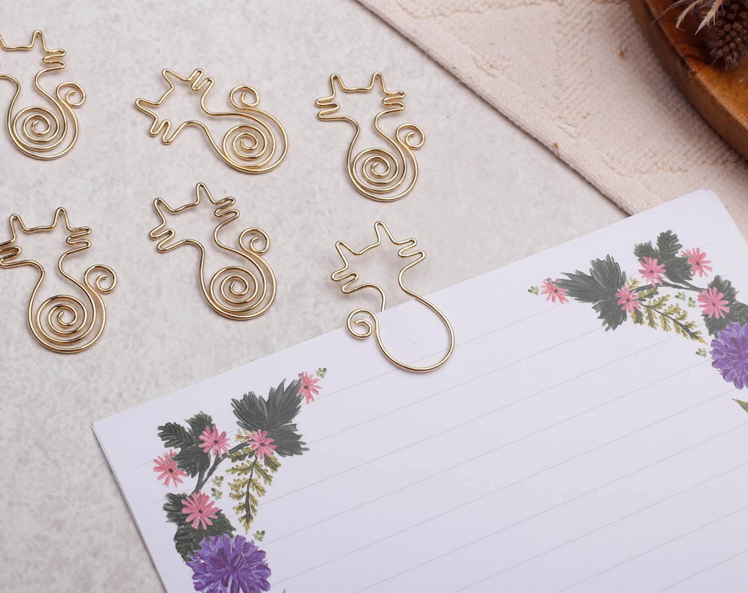 Gold Cat Paper Clips placed on stationery, showcasing their unique cat-shaped design ideal for cat lovers.