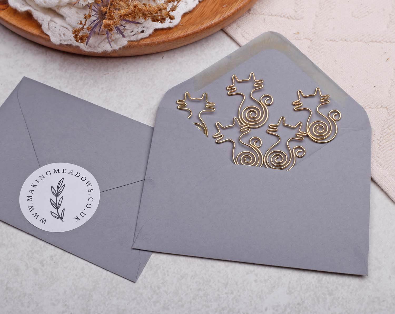 Gold Cat Paper Clips on a gray envelope, charming cat-shaped design for quirky stationery lovers.