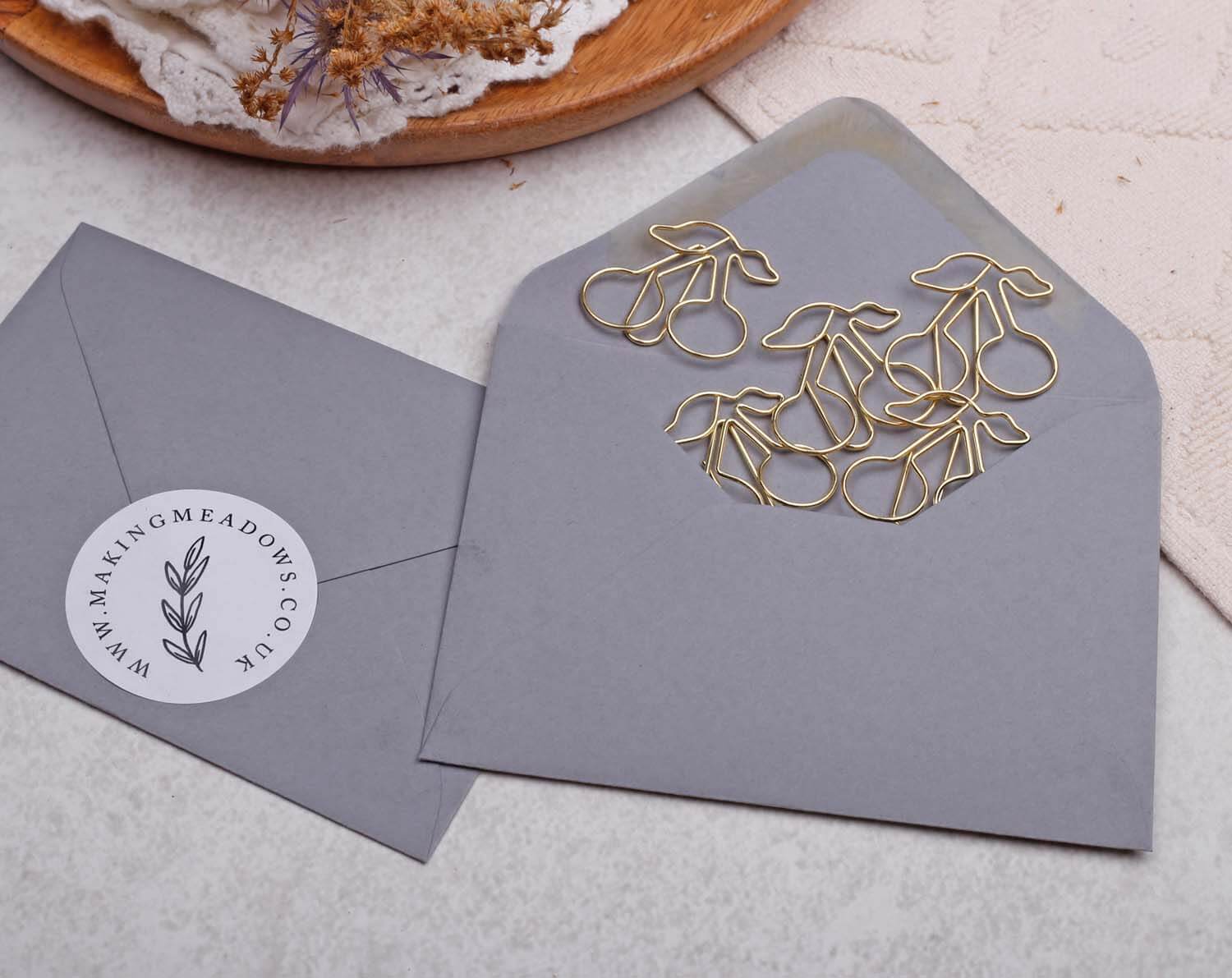 Gold Cherry Paper Clips arranged on a grey envelope, adding a playful touch to stationery.