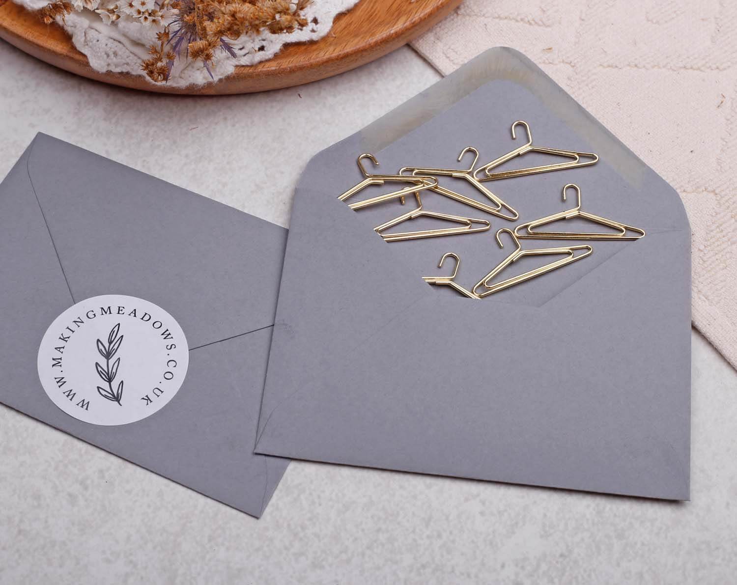 Gold Coat Hanger Paper Clips arranged inside a gray envelope, showcasing a stylish stationery accessory.