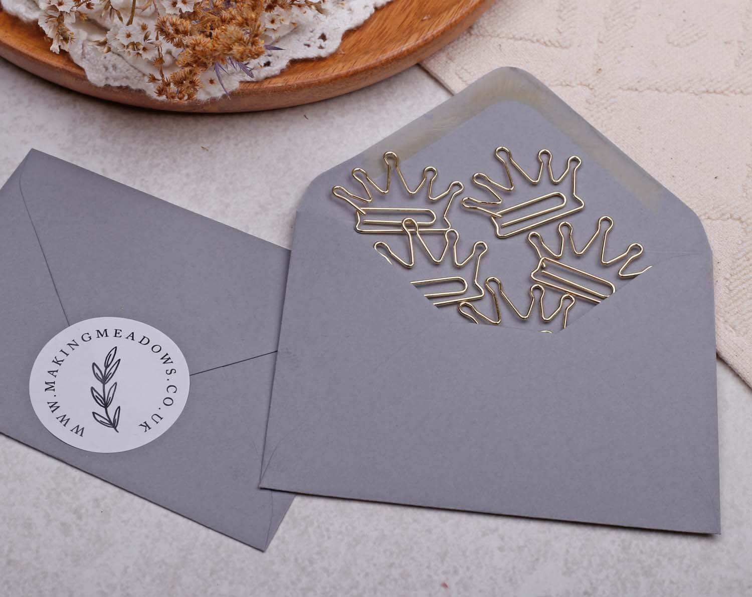 Gold Crown Paper Clips in a grey envelope, showcasing crown-shaped design for elegant stationery.