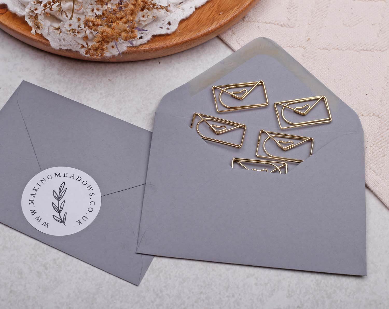 Gold Envelope Paper Clips shaped inside a gray envelope, perfect for stationery lovers and organizing paperwork.