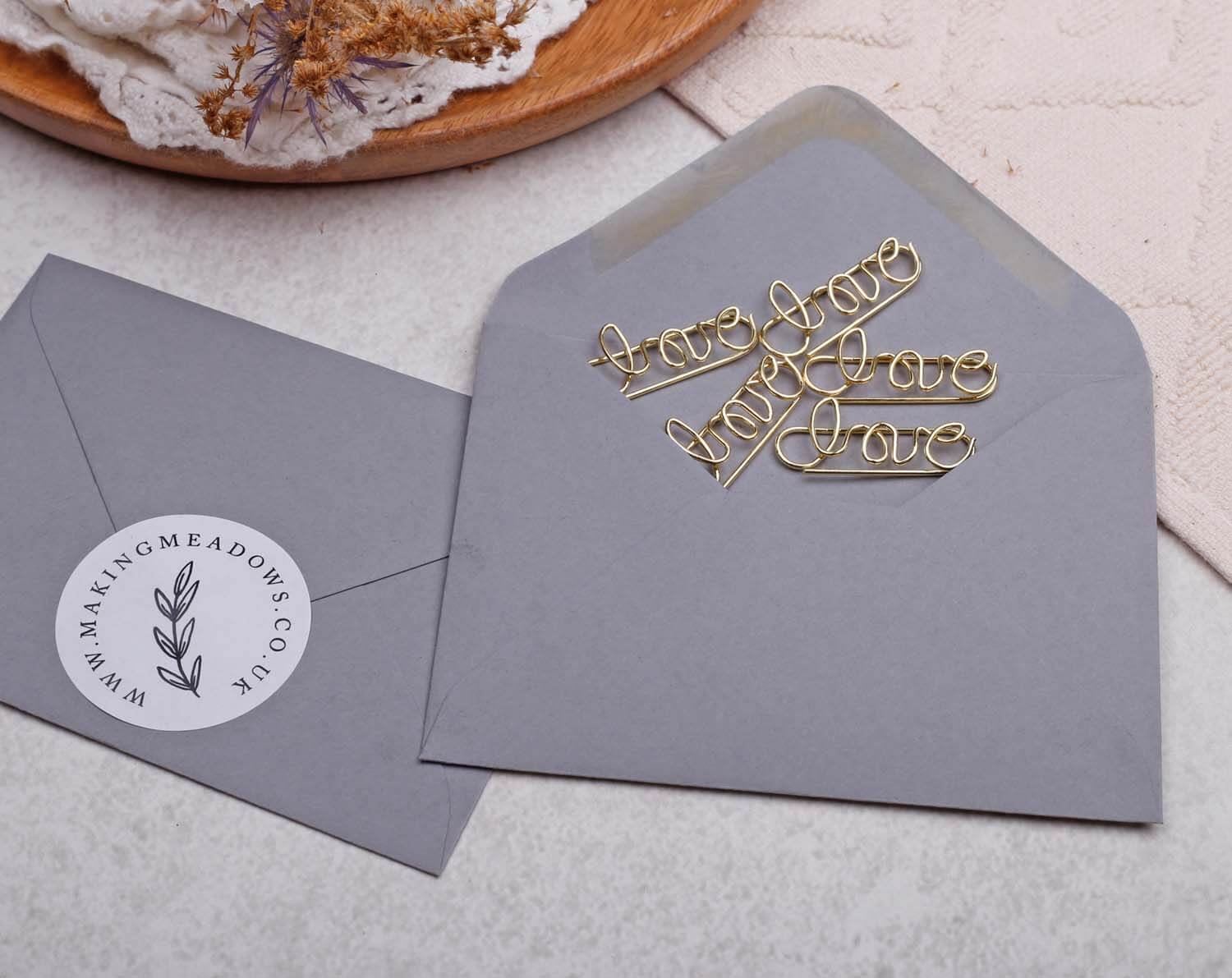 Gold Love Paper Clips - Shaped displayed in a gray envelope with a stylish design.