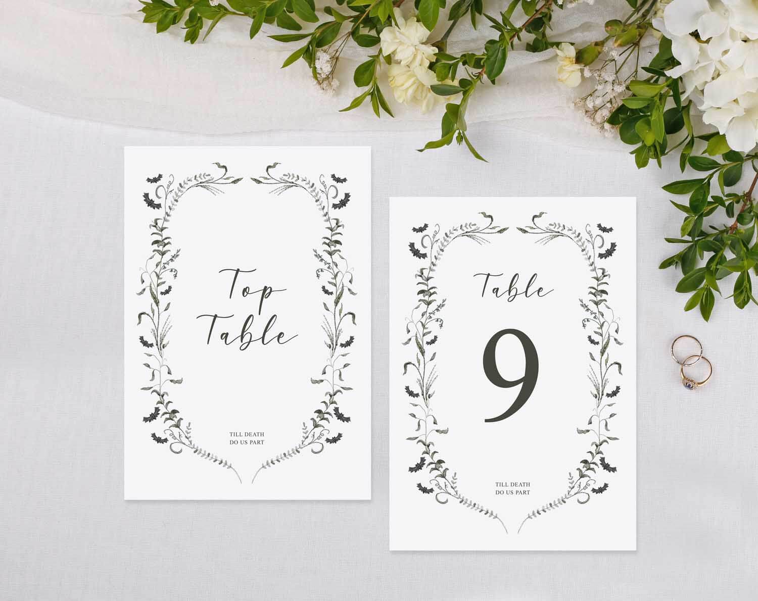 Gothic Wedding Table Numbers displayed on a table with floral arrangement and wedding rings.