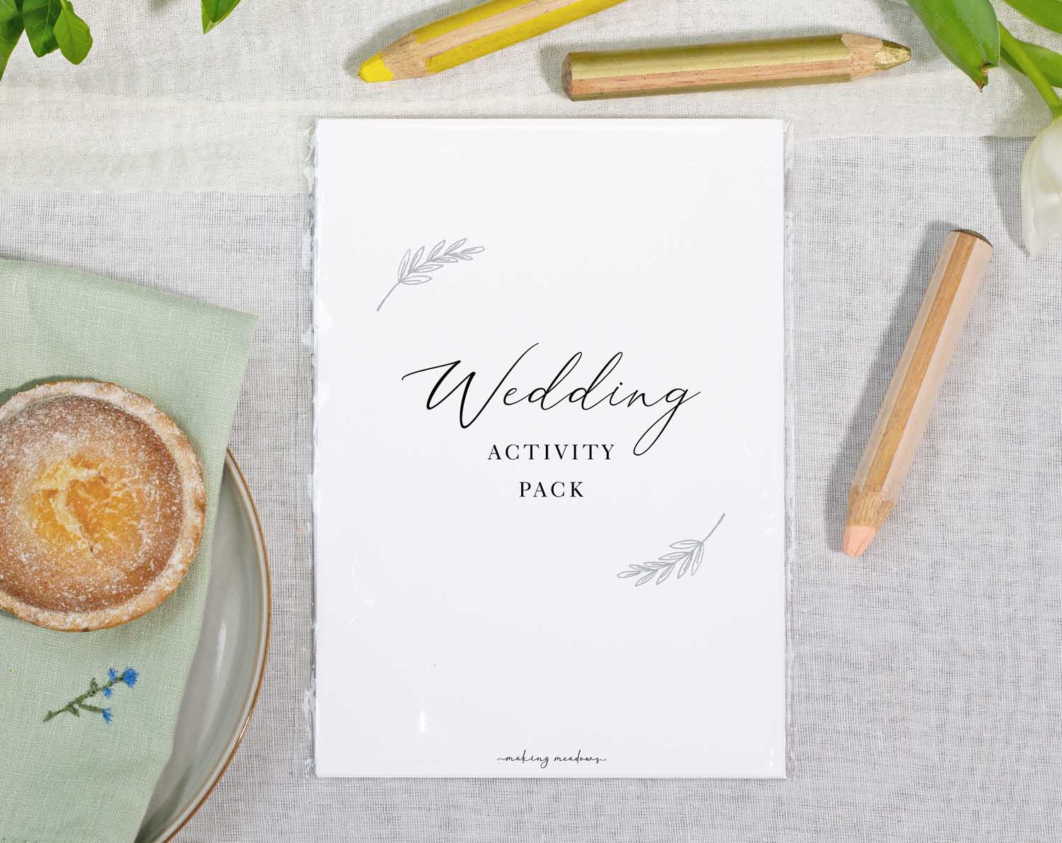 Minimalist Wedding Kids Activity Pack on a table with colored pencils and a pastry.