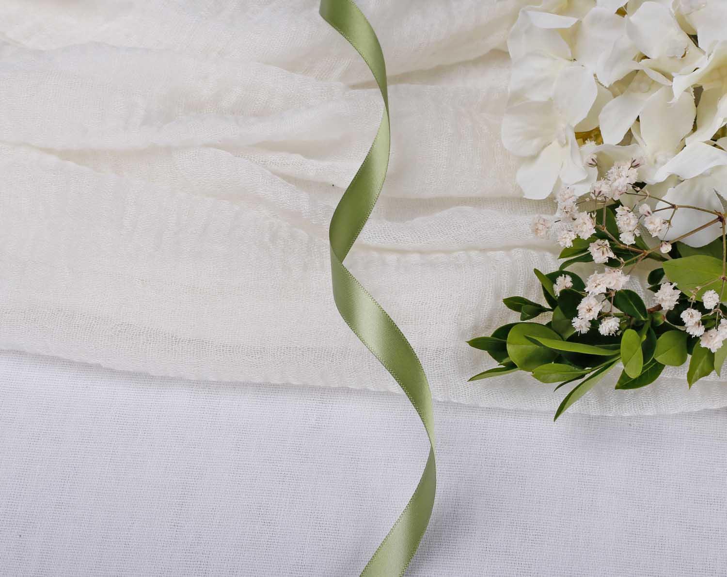 Olive Green Satin Ribbon For Wedding displayed on a white fabric backdrop with flowers, ideal for wedding stationery decoration.