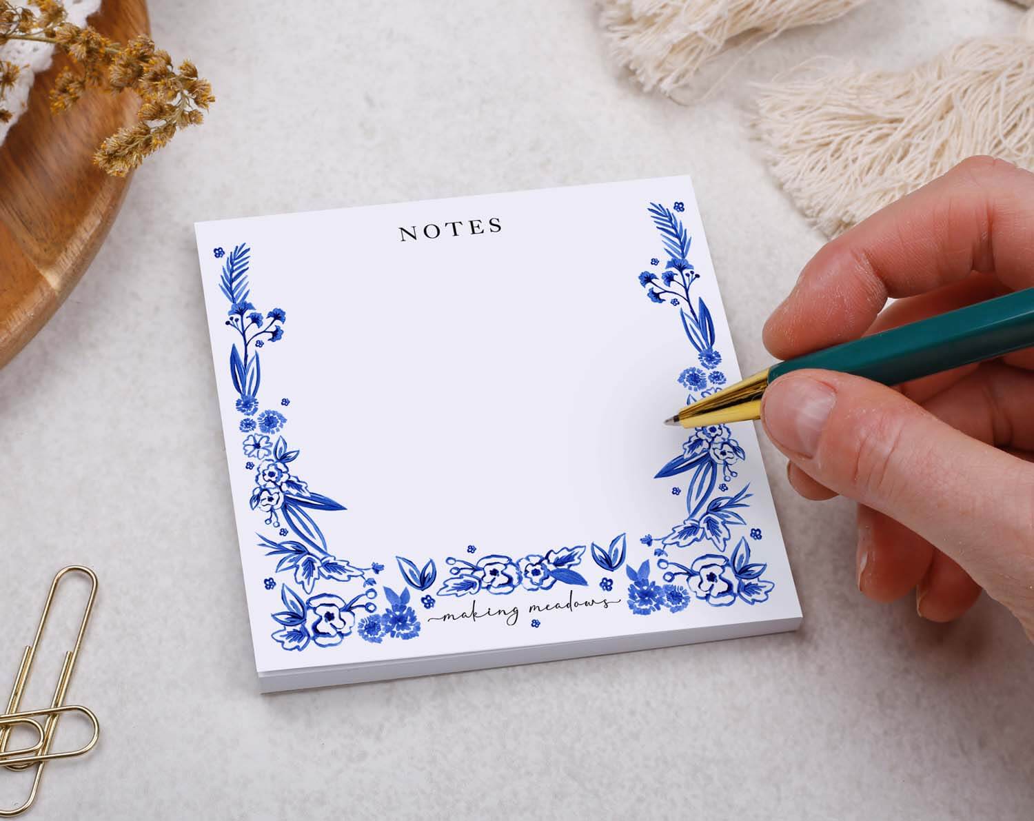 Floral Memo Pad Block with blue floral design and hand holding a pen for making notes.