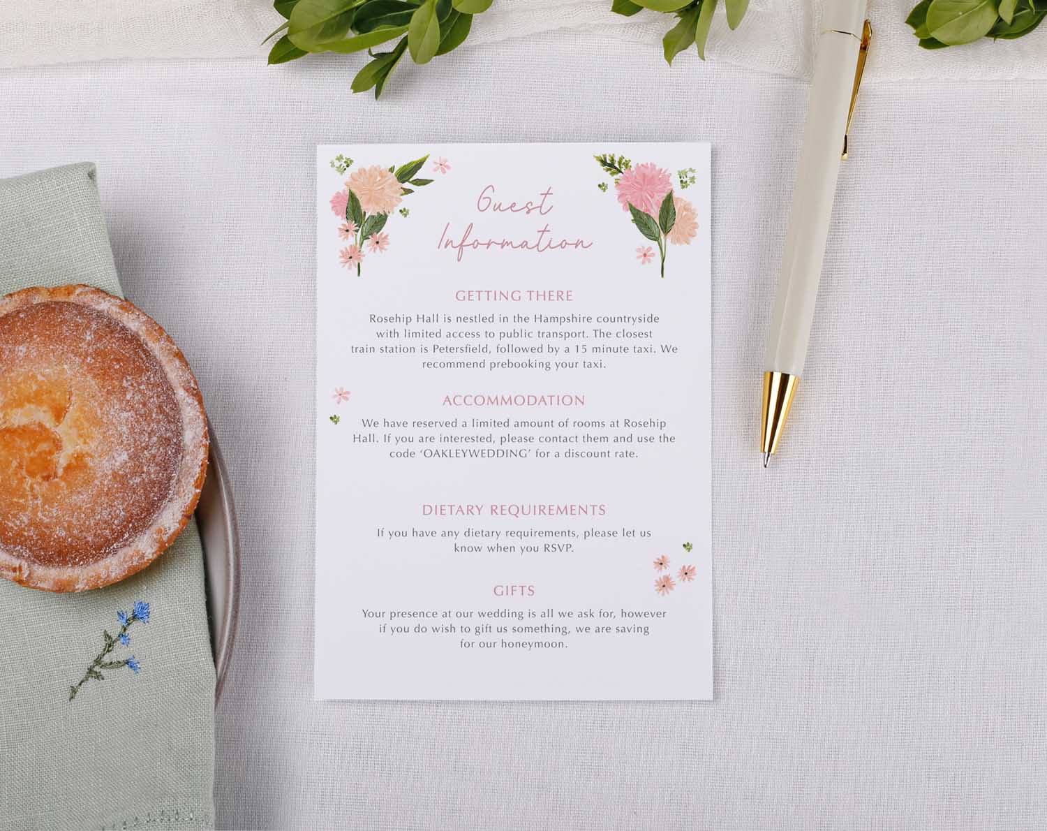 Pink Floral Wedding Information Cards displaying guest information details with floral design and a pen on a table.