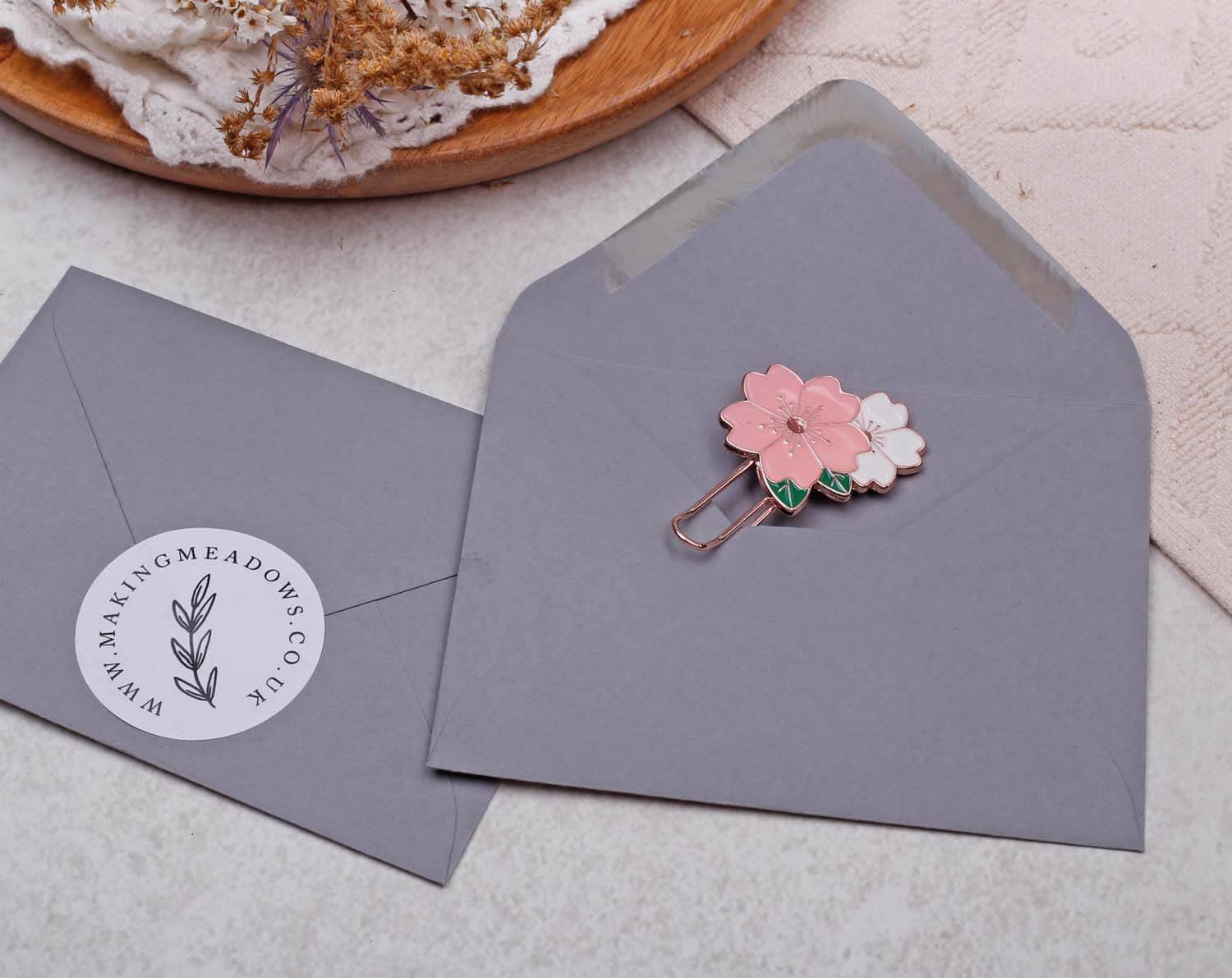Pink Flower Paper Clips displayed on a gray envelope with a floral design.