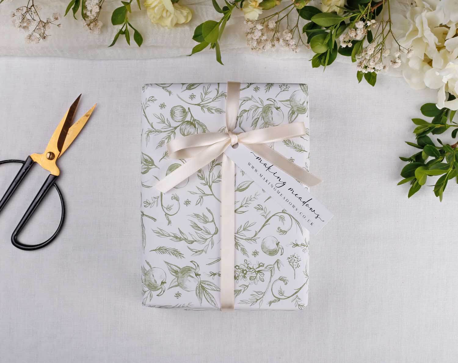 Sage Garden Wedding Wrapping Paper elegantly wraps a gift, adorned with a ribbon and tag, showcasing floral design.