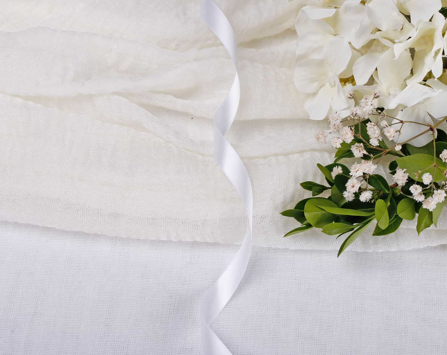 White Satin Ribbon For Wedding elegantly draped alongside ivory fabric and delicate floral arrangements.