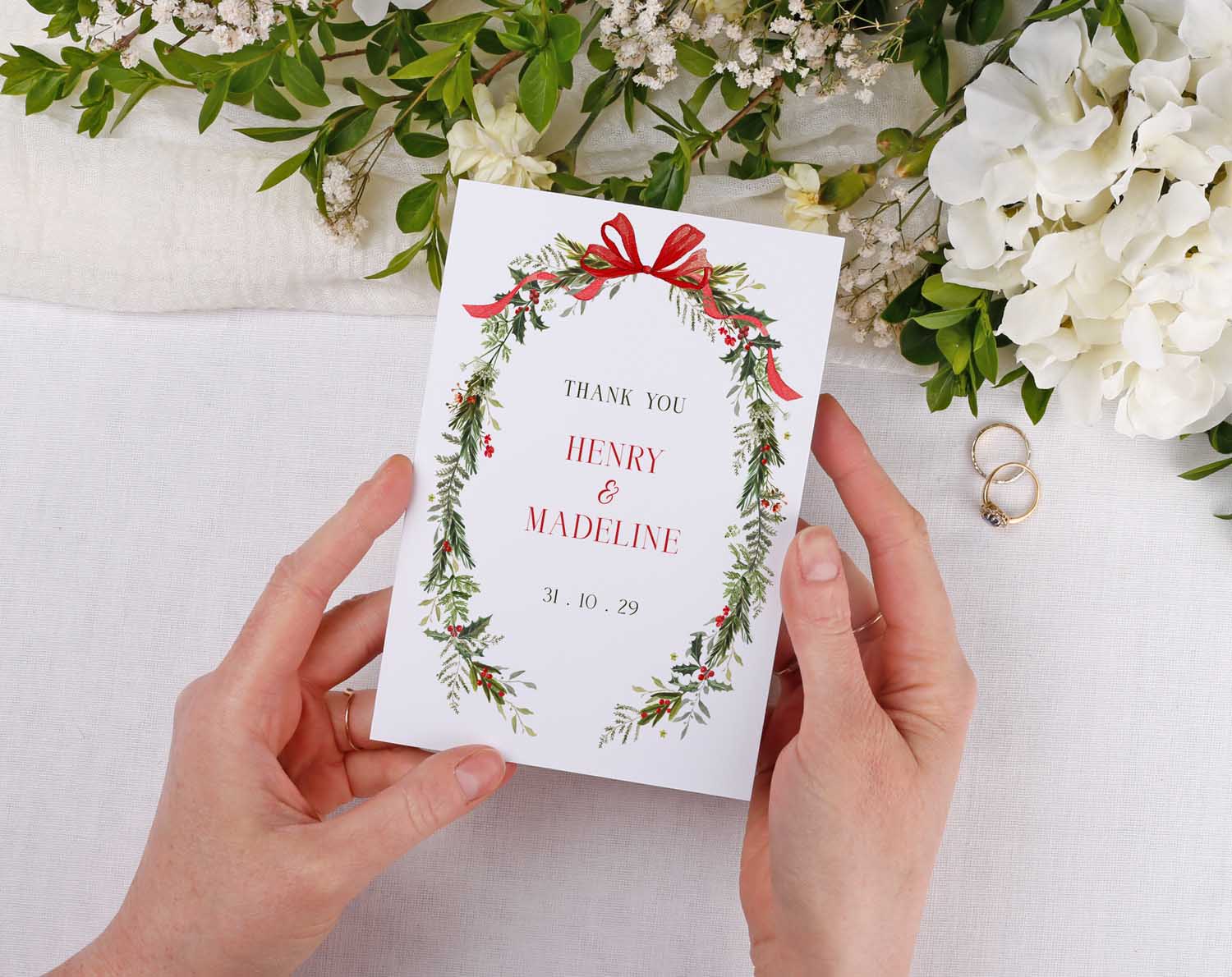 Winter Wedding Thank You Cards featuring a floral design with names and date, held by a person against a neutral background.