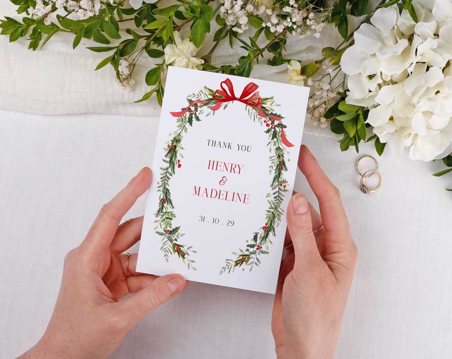 Winter Wedding Thank You Cards featuring a floral design with names and date, held by a person against a neutral background.