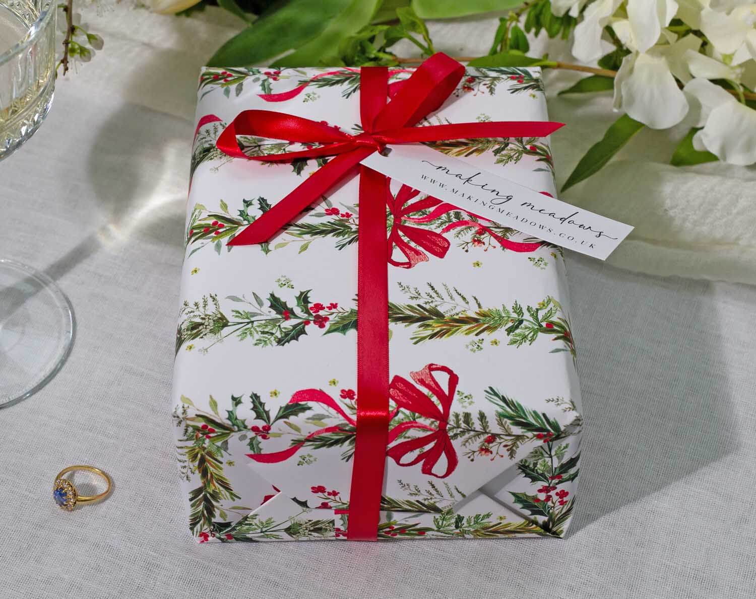 A beautifully wrapped gift in Winter Wedding Wrapping Paper with red ribbon and tag, perfect for wedding celebrations.
