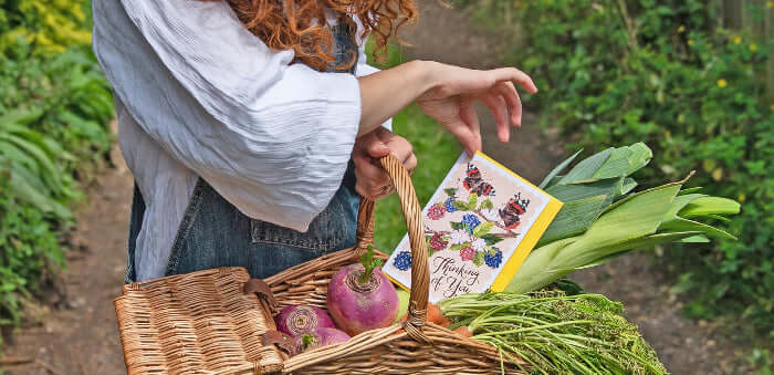 girl holding a basket with a making meadows greeting card in it