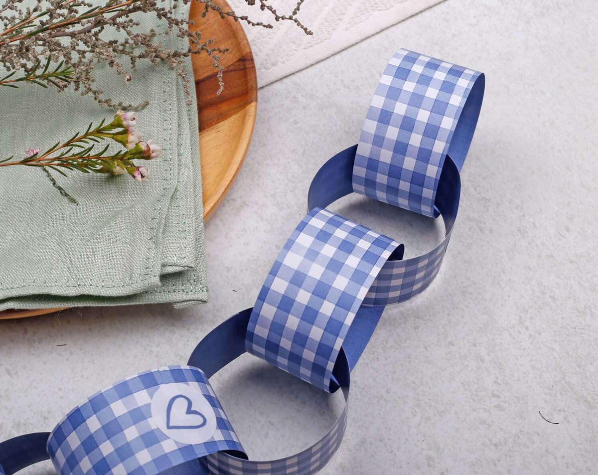 Blue Gingham Paper Chains displayed on a table with a green napkin and dried flowers.