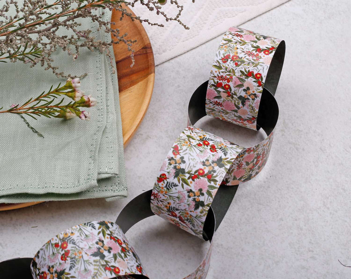 Boho Floral Paper Chains garland displayed on a table with a green napkin and floral decorative elements.