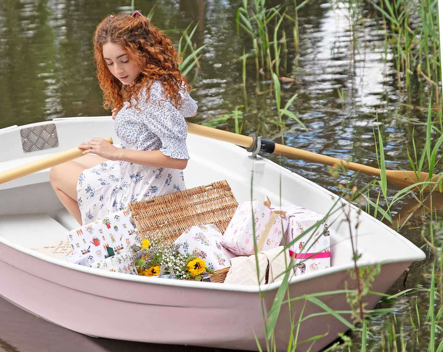A young woman with curly hair rowing a small boat filled with eco-friendly products, showcasing a commitment to sustainability.