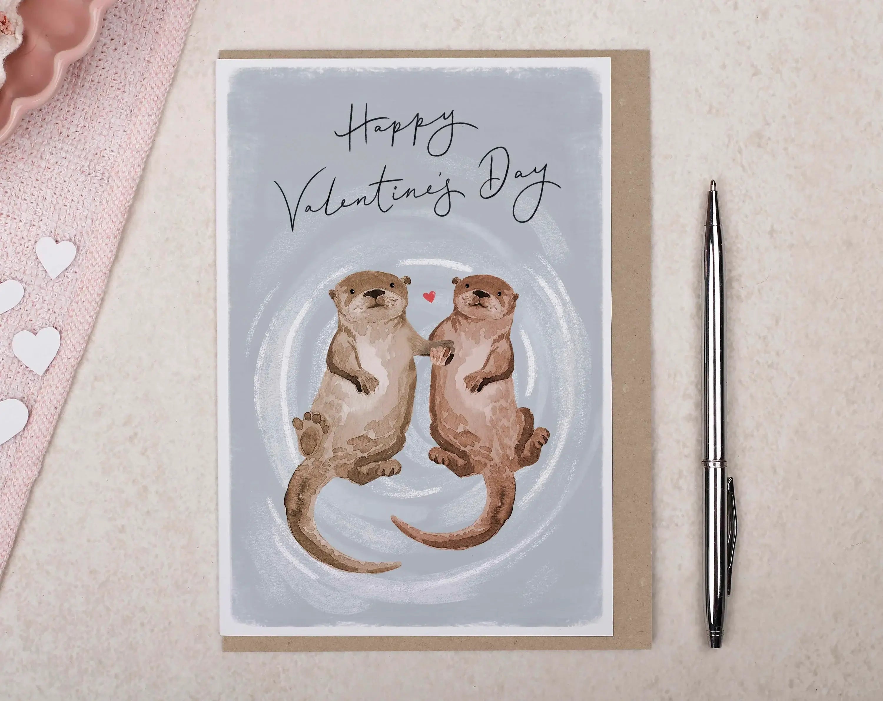 What To Write In A Valentine Card with cute otters holding paws and a heart illustration.