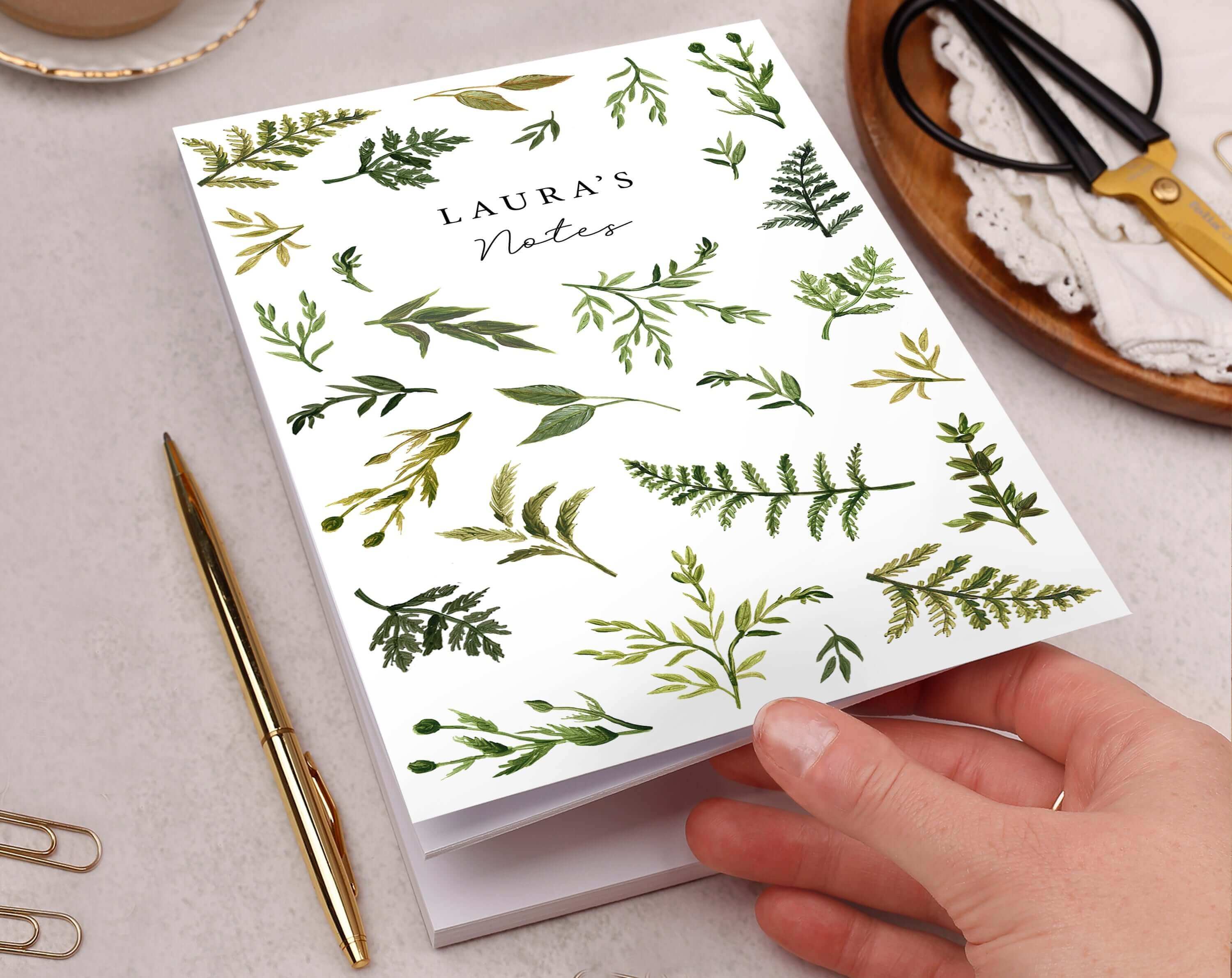 A hand holding a floral notes notebook, showcasing tips on how to stay organised with stationery.