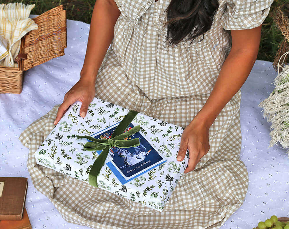 Eco Friendly Wrapping Paper beautifully wrapped gift held by a person in a checkered dress, surrounded by nature.