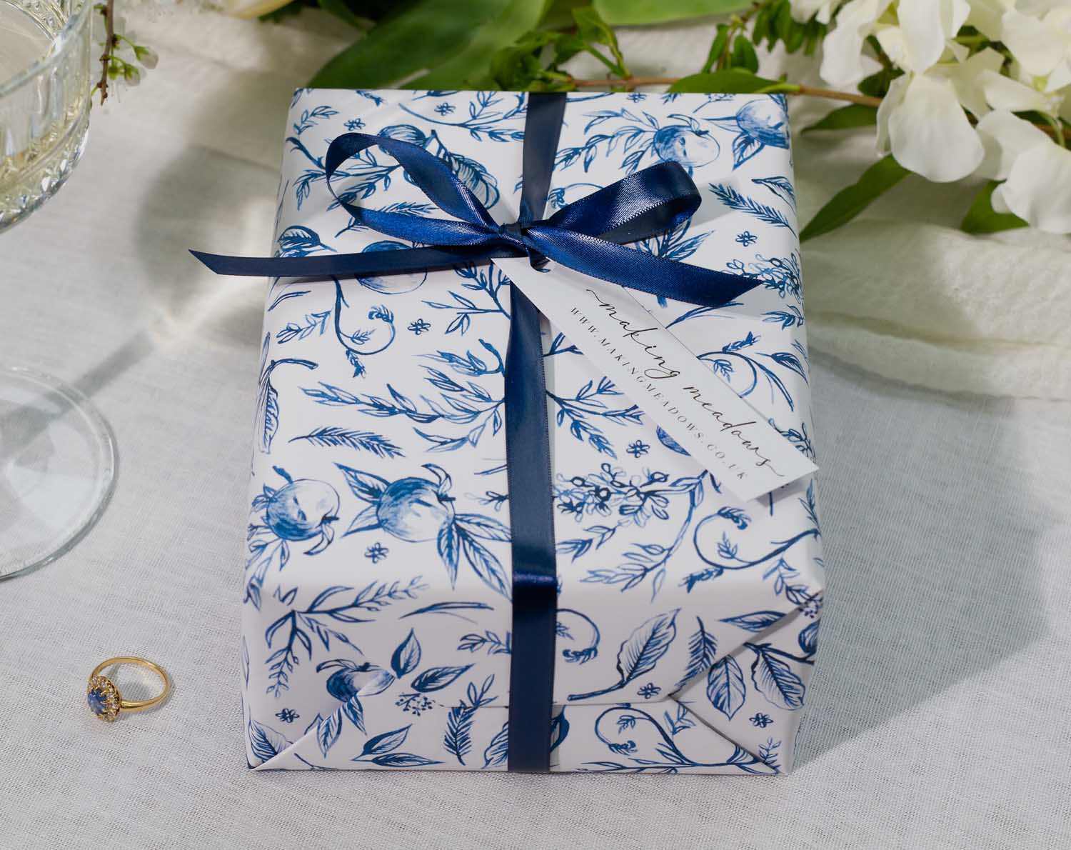 Beautifully wrapped gift in Luxury Wrapping Paper For Weddings with floral design and blue ribbon.