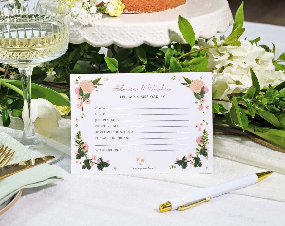 Pink Floral Wedding Advice Cards placed on a table with floral decorations and a pen for guest messages.