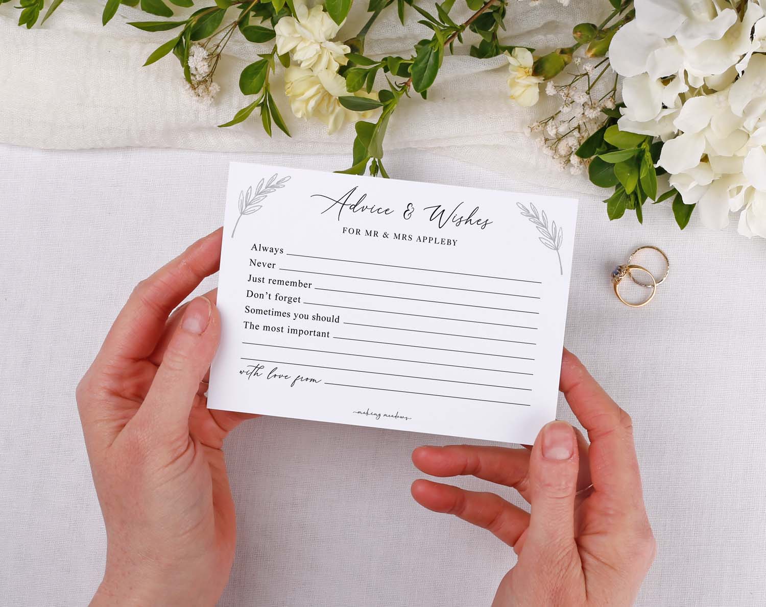 Minimalist Wedding Advice Cards held in hands with floral decor and wedding rings, inviting guest messages.
