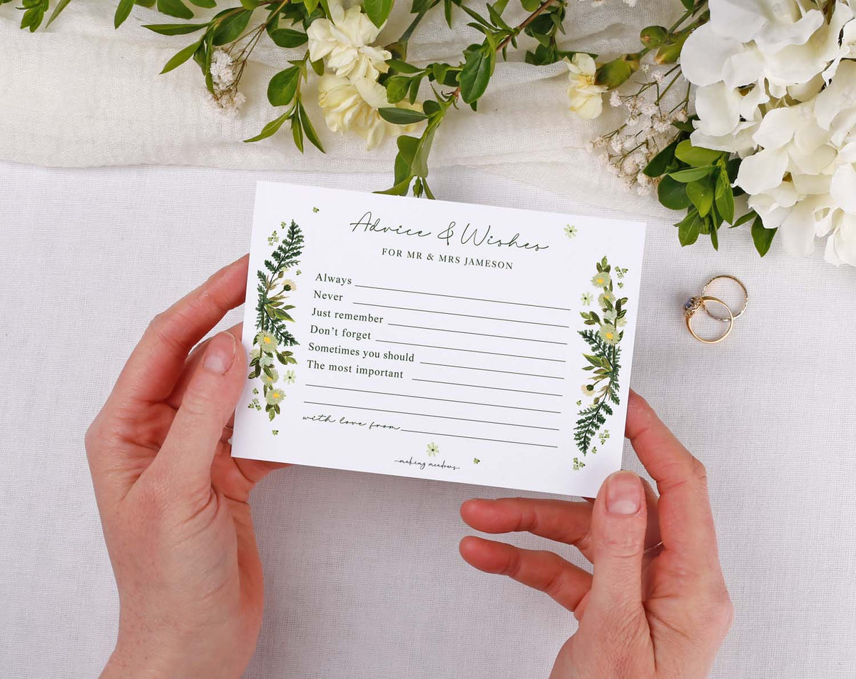 Botanical Wedding Advice Cards held by hands, featuring a floral design with spaces for guest messages.