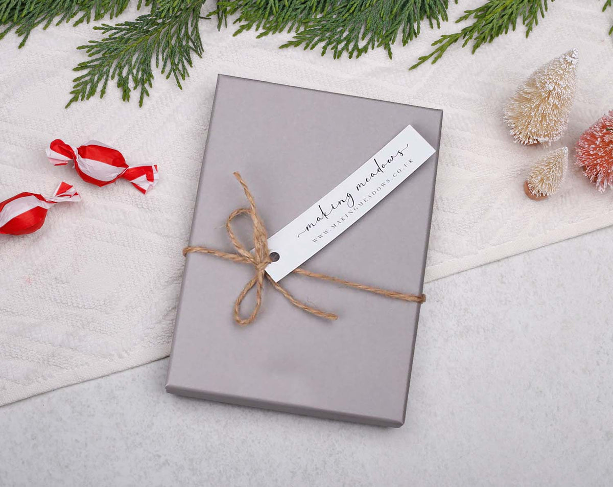 Beautifully wrapped gift box with a rustic tag on a festive background, perfect for Baby's First Christmas Advent.