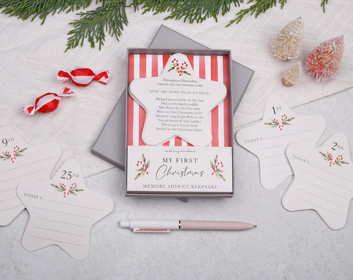 Image of Baby's First Christmas Advent Keepsake with memory cards and holiday decorations set on a table.