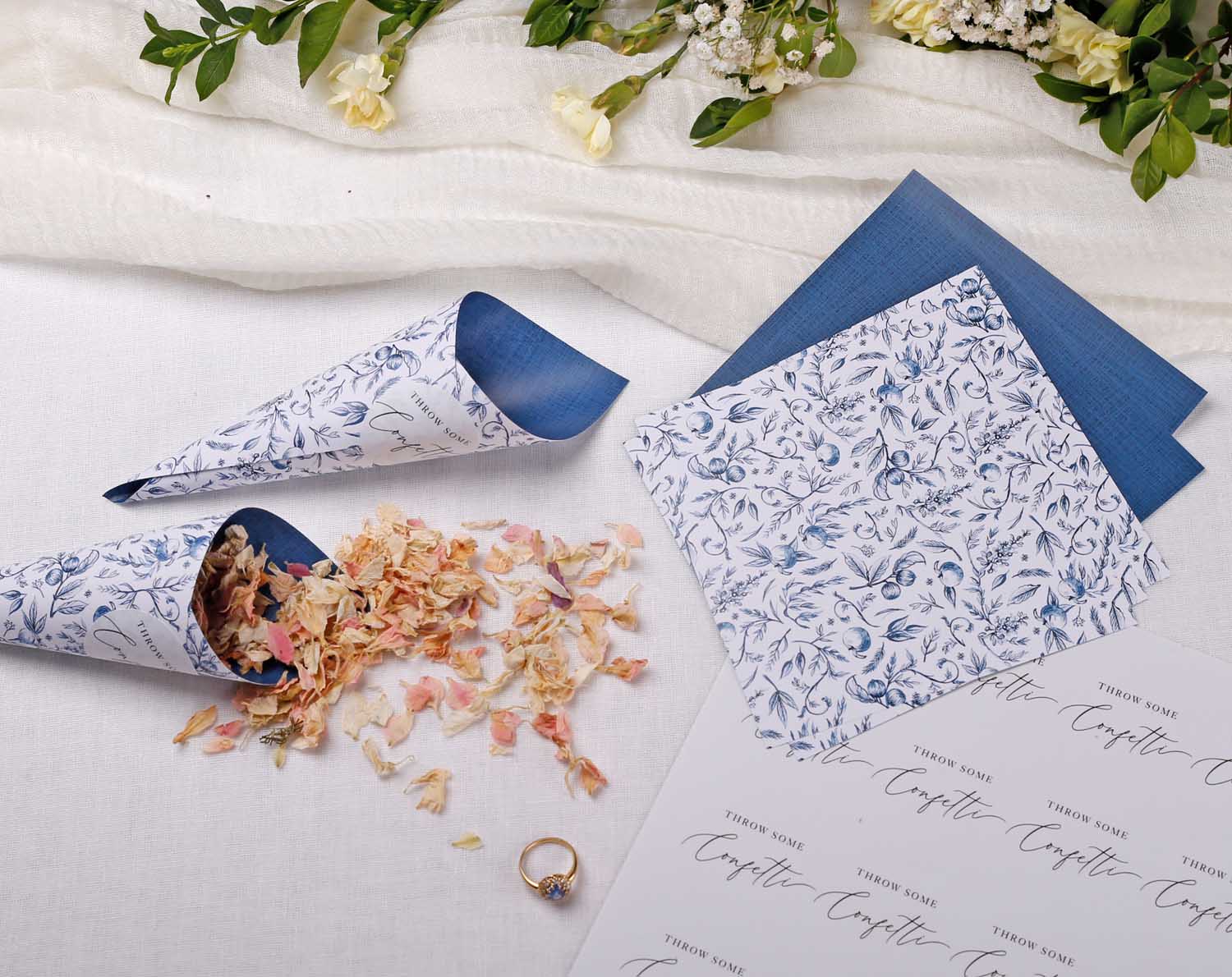 Blue Garden Wedding Confetti Cones elegantly displayed with floral confetti, napkins, and a ring on a table setting.