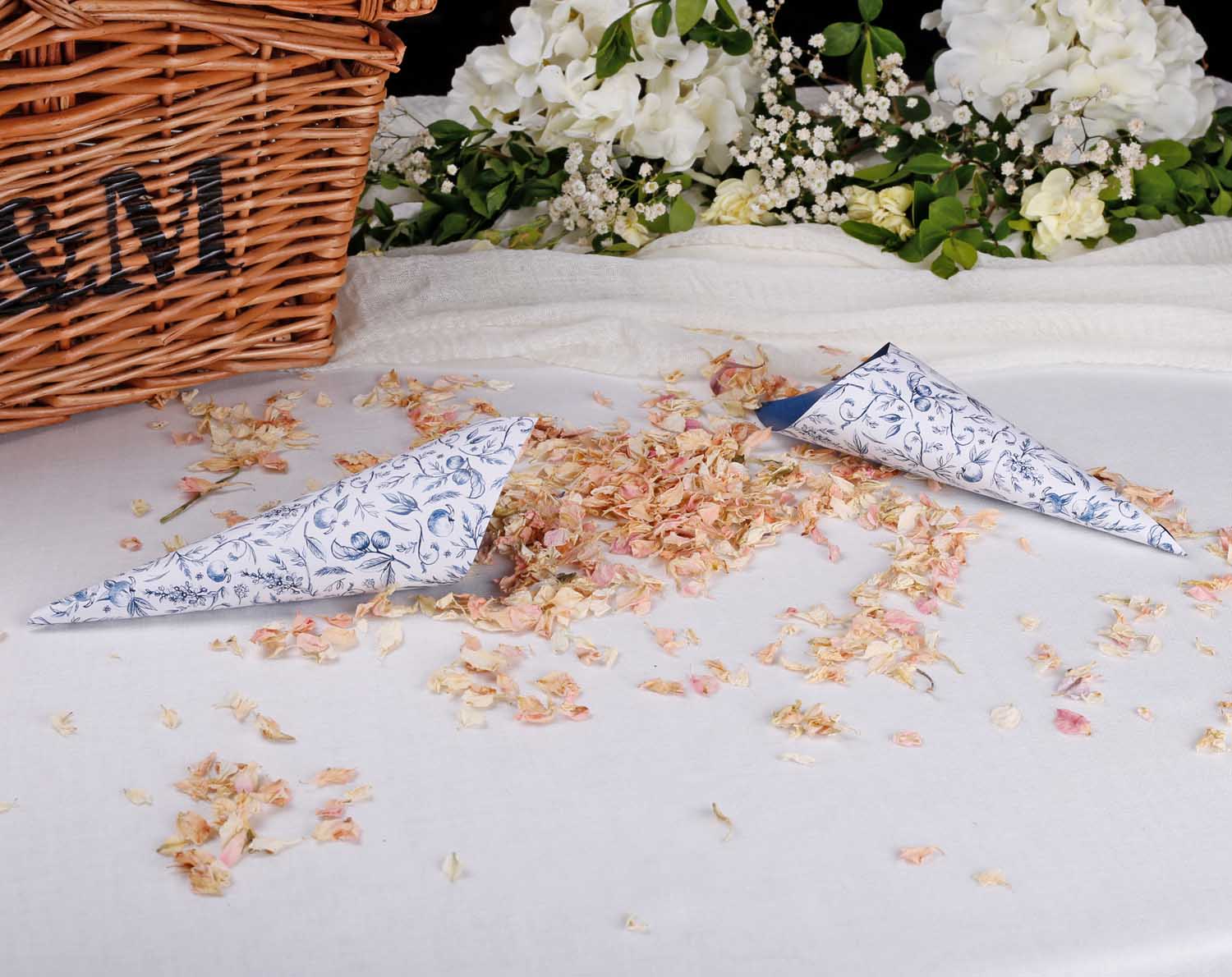 Blue Garden Wedding Confetti Cones beautifully scattered on a table with flower petals, perfect for a wedding ceremony.