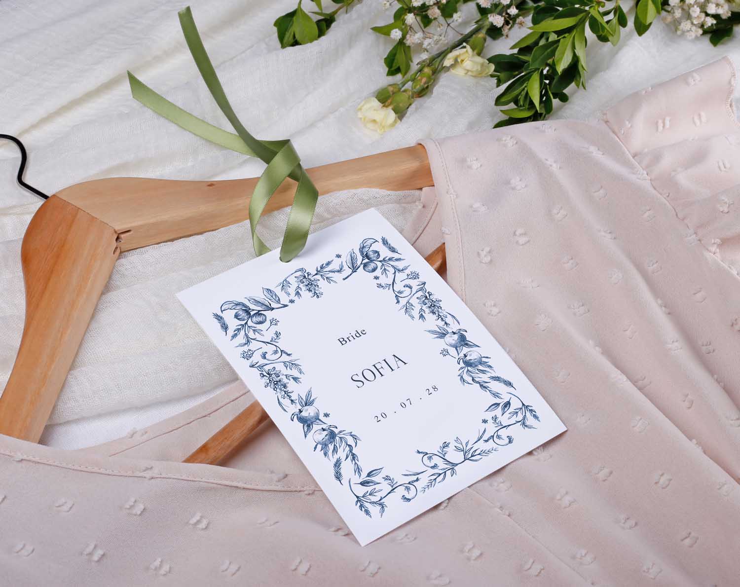 Blue Garden Wedding Hanger Tags for bridal party tied to a wooden hanger with a soft pastel dress.