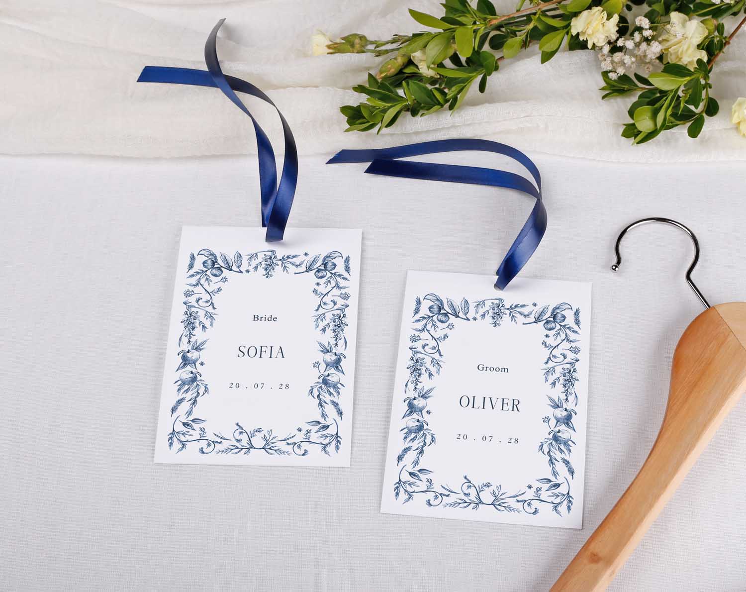 Blue Garden Wedding Hanger Tags hanging with blue ribbons, personalized for bride and groom with floral design.